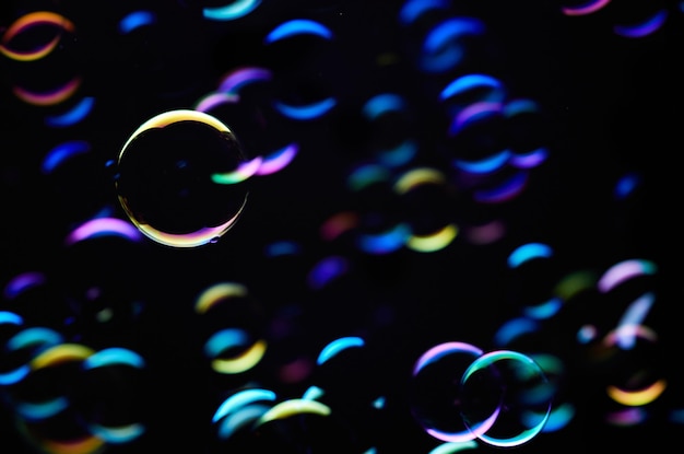 Uno sfondo nero con bolle colorate che fluttuano nell'aria.