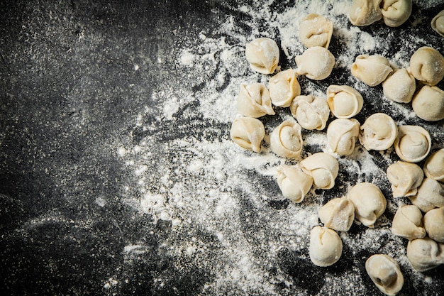 Uno sfondo nero con sopra un mazzetto di pasta cruda e la parola pasta in alto.