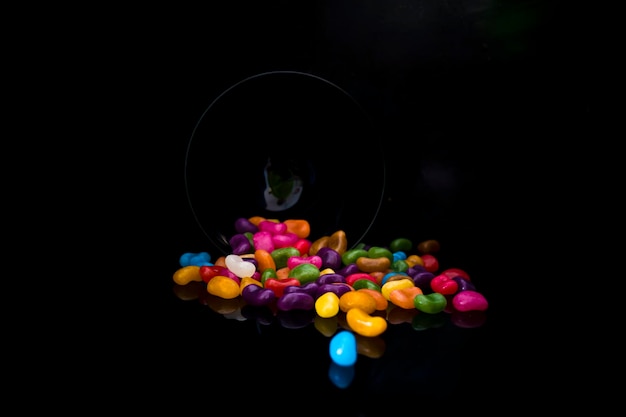 Uno sfondo nero con una ciotola di caramelle colorate.
