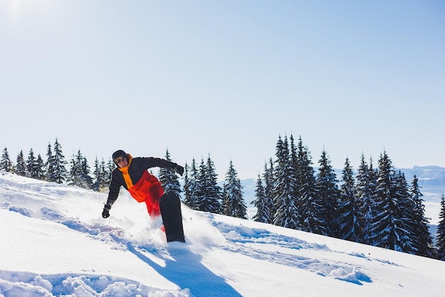 Uno snowboarder cammina lungo un pendio nevoso in inverno sulla neve Snowboard freeride invernale