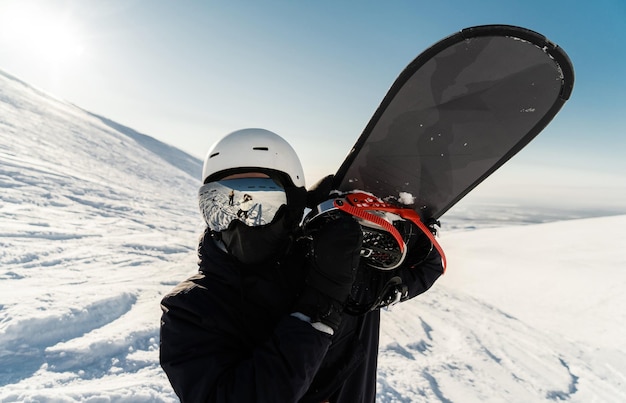 Uno snowboarder con casco e occhiali in tenuta invernale conquisterà la cima della montagna