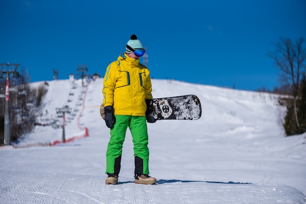 Uno snowboarder guarda il suo snowboard in una luminosa giornata di sole.