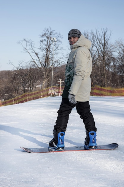 Uno snowboarder si trova in cima a una pista da sci innevata e si prepara a scendere Snowboarder prima della discesa sport invernali estremi Foto verticale