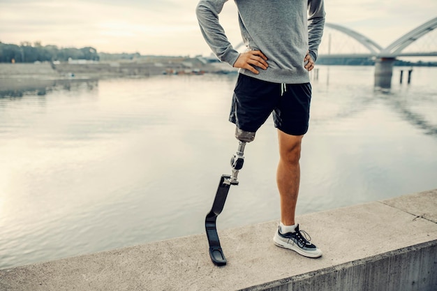 Uno sportivo disabile con gamba artificiale in piedi in banchina con le mani sui fianchi