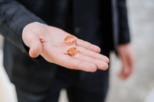 Uno sposo che tiene le fedi nuziali nel suo primo piano della mano