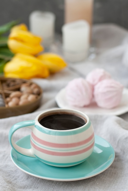 Uno spuntino gustoso: una tazza di caffè, un piatto di zefiro e una scatola di dolci.