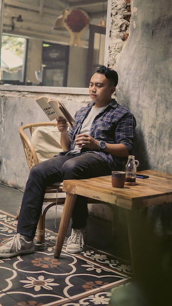 Uno studente che si gode un caffè mentre legge un libro nel pomeriggio