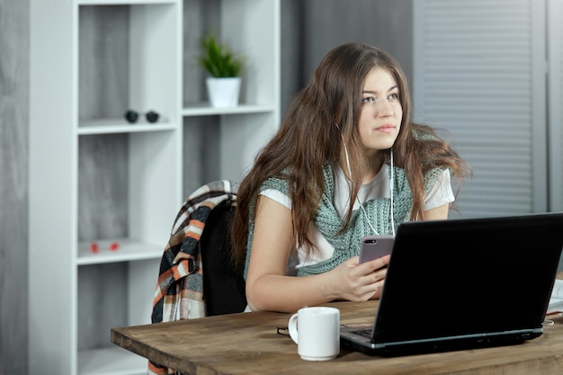 Uno studente concentrato fa i compiti a casa, seduto alla scrivania con un laptop