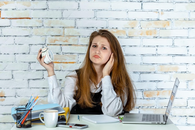 Uno studente sconvolto seduto e tenendo l'orologio Foto di alta qualità