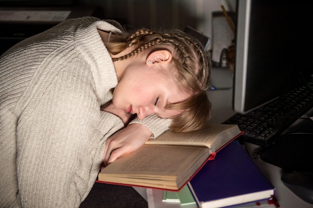 Uno studente stanco si è addormentato su un libro vicino al computer di notte