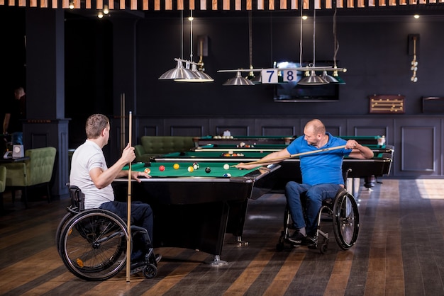 Uomini adulti con disabilità in sedia a rotelle giocano a biliardo nel club