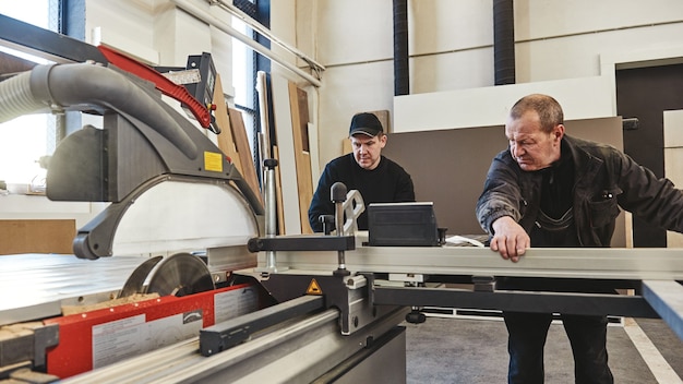 uomini al lavoro segando legno sega circolare una macchina che sega pannelli di particelle di legno e fibra di legno