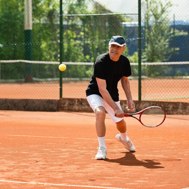 Uomini anziani che colpiscono palla sul campo da tennis