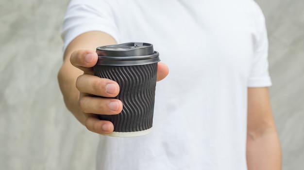 Uomini che tengono una tazza di caffè su sfondo grigio.