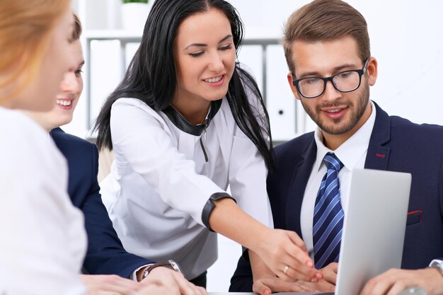 Uomini d'affari a una riunione in ufficio. Concentrarsi sulla donna che punta verso il computer portatile.