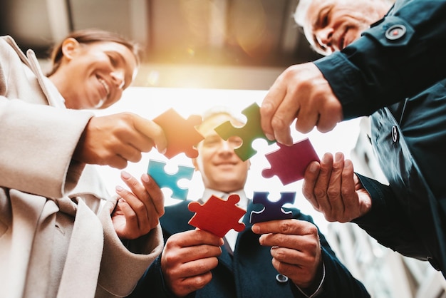 Uomini d'affari che lavorano insieme per costruire un puzzle come concetto di partnership e integrazione del lavoro di squadra