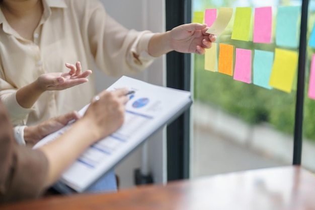 Uomini d'affari che lavorano su foglietti adesivi e annotano idee creative su post-it per investitori professionali che avviano attività di progetto