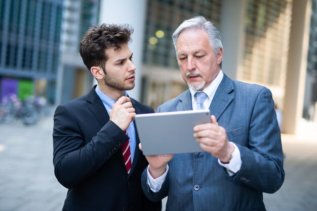 Uomini d'affari che lavorano su un tablet all'aperto