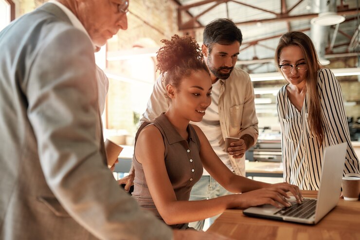 Foto uomini d'affari di successo del team che guardano il laptop mentre lavorano insieme nell'ufficio moderno