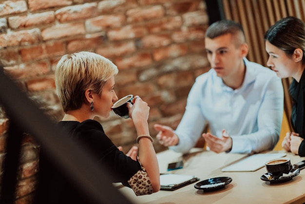 Uomini d'affari felici che sorridono allegramente durante una riunione in una caffetteria Gruppo di professionisti d'impresa di successo che lavorano in squadra in un luogo di lavoro multiculturale