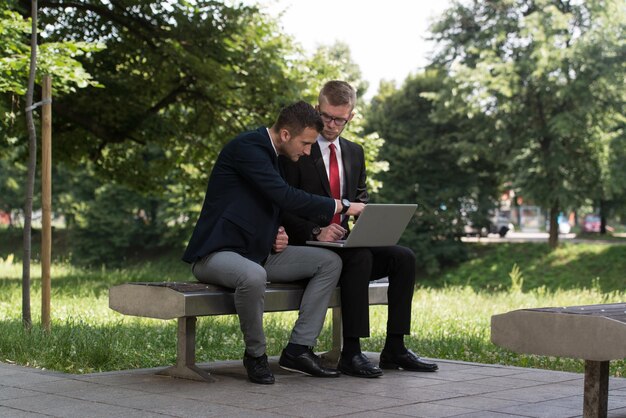 Uomini d'affari felici che utilizzano Tablet Pc fuori su una panchina nel parco