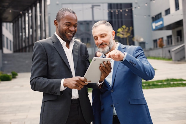 Uomini d'affari in piedi davanti a un ufficio moderno e utilizzando un tablet