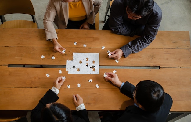 Uomini d'affari in possesso di puzzle bianco Costruzione di relazioni di brainstorming vista dal piano di lavoro di squadra