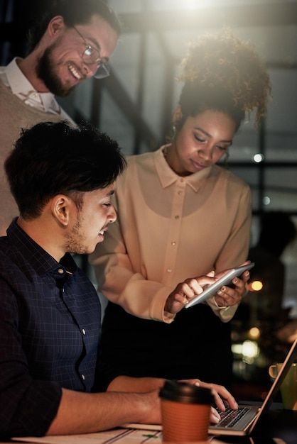 Uomini d'affari notturni e lavoro di squadra sulla tecnologia tablet per pianificare la ricerca o la collaborazione in ufficio buio Dipendenti di diversità che lavorano fino a tardi online nella strategia digitale e nel gruppo dell'agenzia di design