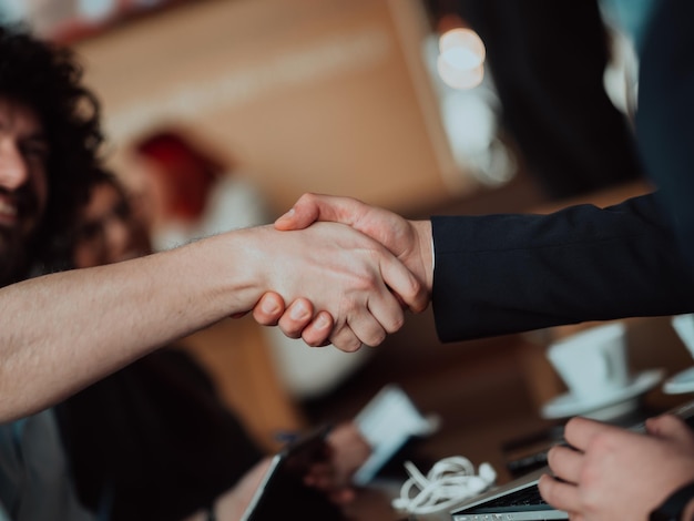 Uomini d'affari o avvocati che si stringono la mano per finire la riunione o la negoziazione in un ufficio soleggiato. Stretta di mano aziendale e partnership