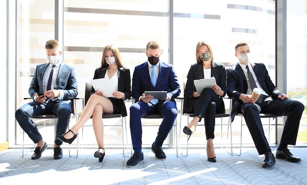 Uomini d'affari stressanti in attesa di un colloquio di lavoro con maschera facciale, quarantena di allontanamento sociale durante l'effetto COVID19