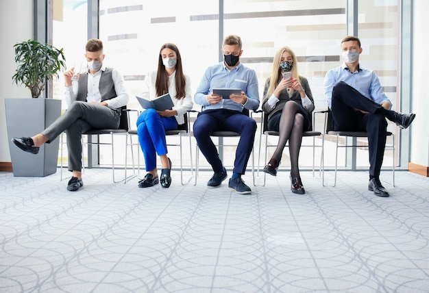 Uomini d'affari stressanti in attesa di un colloquio di lavoro con maschera facciale, quarantena di allontanamento sociale durante l'influenza del COVID19.