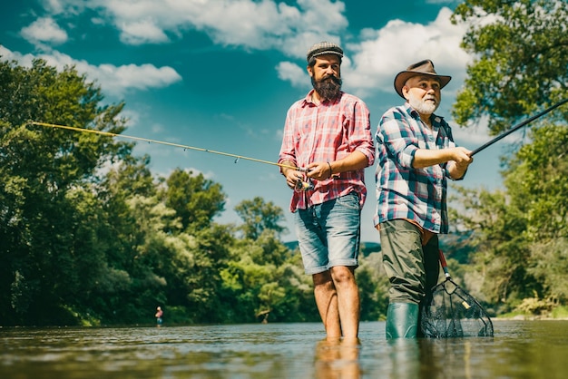 Uomini hobby e ricreazione Pescatori di successo pescare il pesce Fisher pensionamento Imprenditore in pensione in tuta con canna da pesca Amicizia maschile Nonno e pesca del drandson