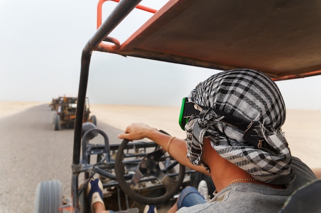 Uomini in sella a una carrozzina nel deserto