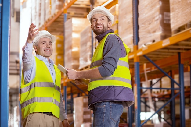 Uomini positivi felici che sorridono mentre si divertono a lavorare insieme