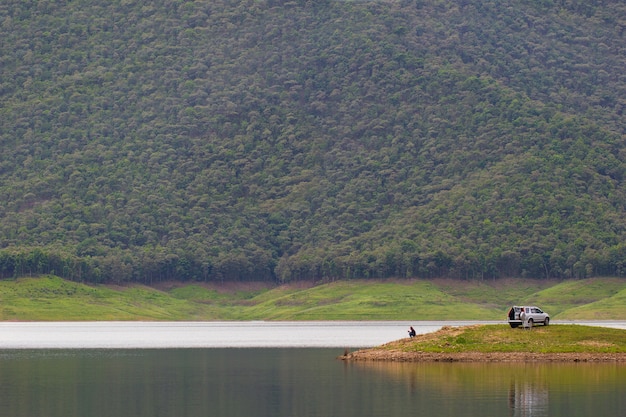 Uomini seduti e che pescano sull'isola presso la diga tra le montagne.