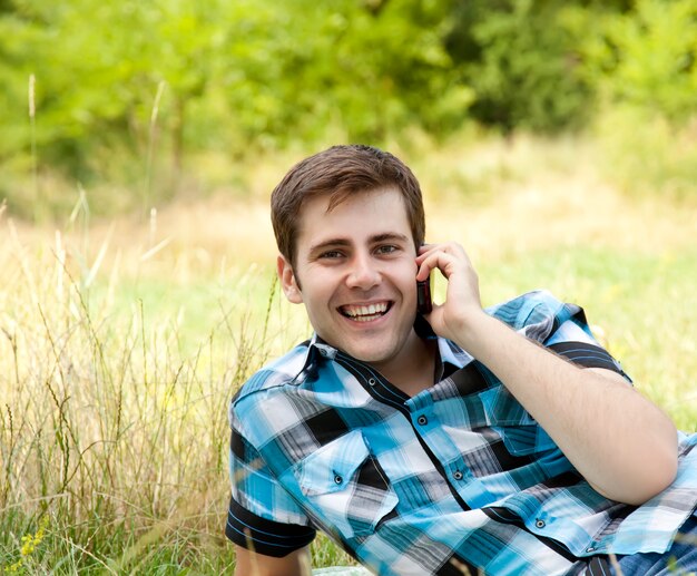 Uomini sorridenti con il telefono cellulare all'aperto.