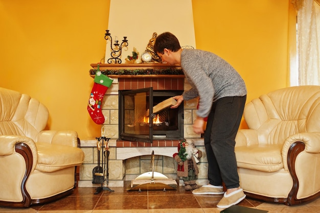 Uomo a casa da un caminetto nel caldo soggiorno il giorno d'inverno.