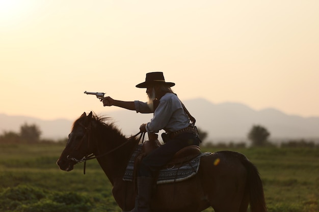 Uomo a cavallo mentre spara con una pistola contro il cielo