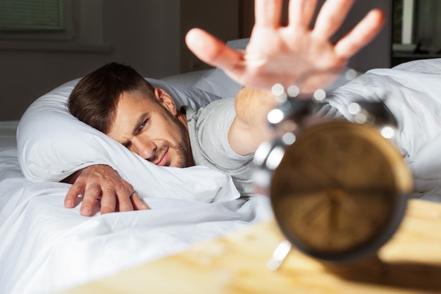 uomo a letto che cerca la sveglia