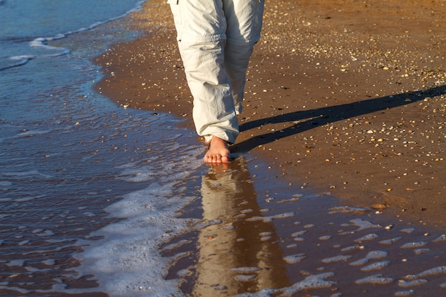 uomo a piedi nudi che cammina sulle onde del surf