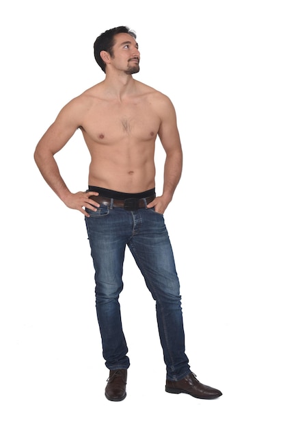 Uomo a torso nudo e con jeans blu che guarda di lato su sfondo bianco