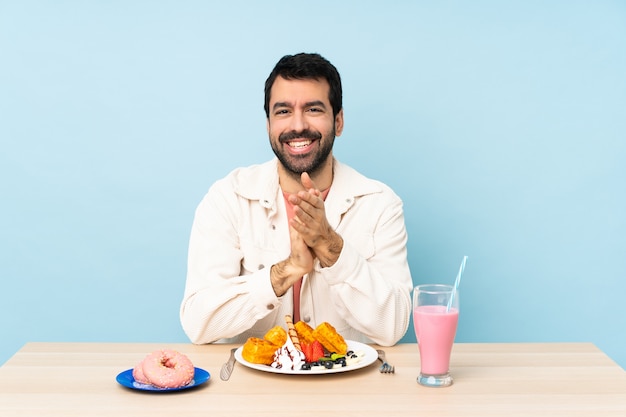 Uomo a un tavolo con cialde per la colazione