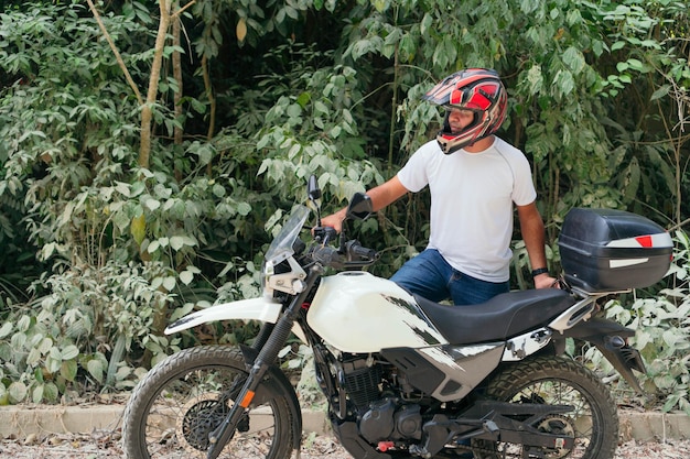 Uomo accanto alla sua moto su una strada rurale