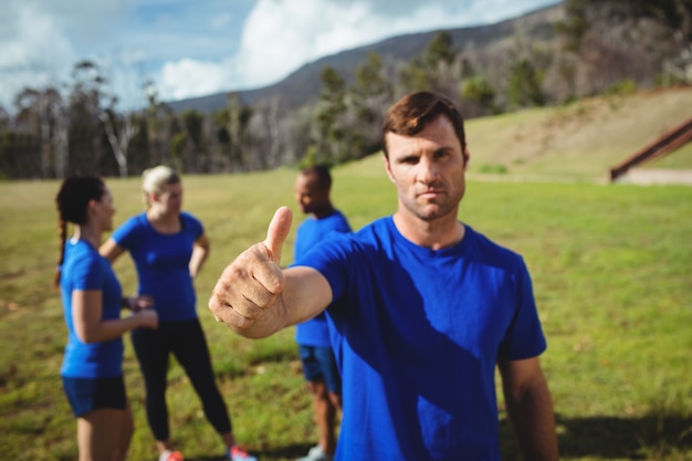 Uomo adatto che mostra i pollici in su nel bootcamp