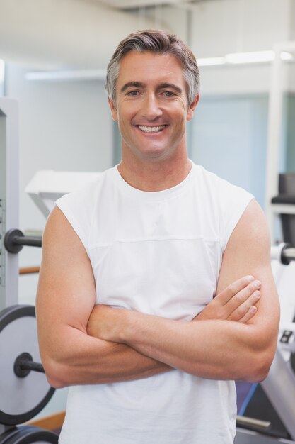 Uomo adatto che sorride alla macchina fotografica nello studio di forma fisica