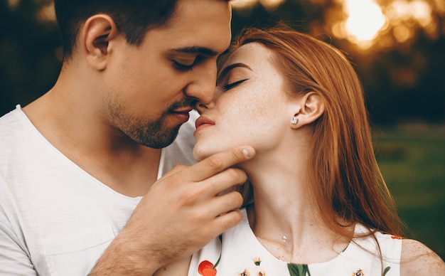 Uomo adorabile e donna che bacia contro il tramonto all'aperto