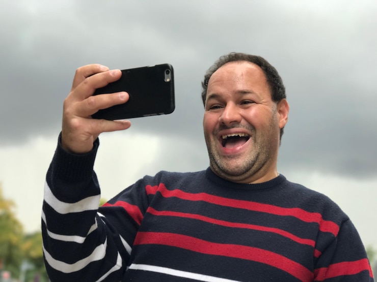 Foto uomo adulto allegro che si fa un selfie contro un cielo nuvoloso