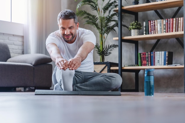 Uomo adulto bello che fa esercizio di fitness a casa