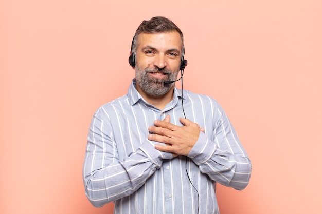 Uomo adulto bello sentirsi romantico, felice e innamorato, sorridendo allegramente e tenendosi per mano vicino al cuore