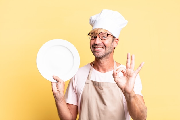 Uomo adulto biondo bello chef con un piatto vuoto